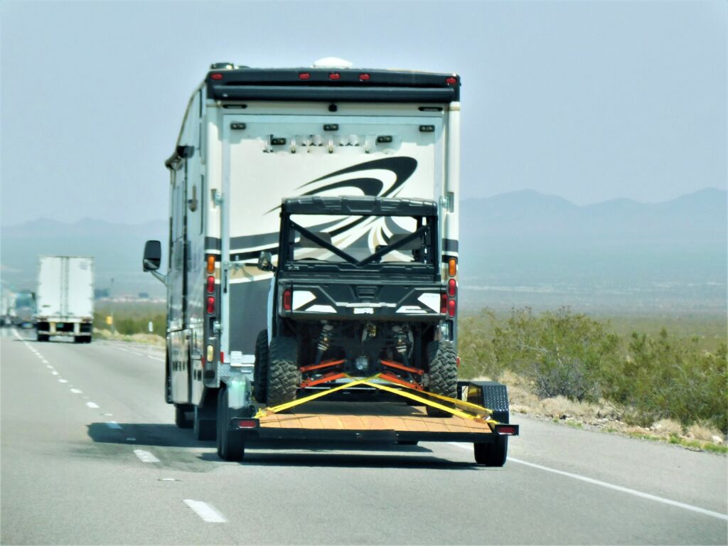 RV driving on a highway towing a side-by-side vehicle